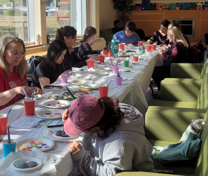Participants in the Scatter Stones event paint rocks with messages of respect, consent, compassion, and care.